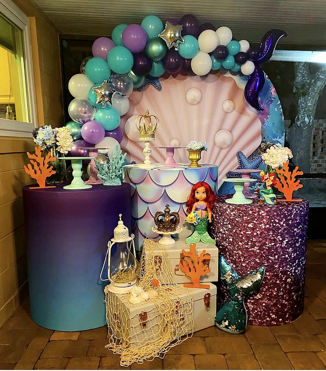 Mermaid under-the-sea setup with seashell backdrop and purple and teal balloons